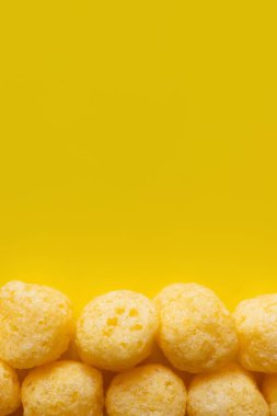 top view of puffed and tasty cheese pops on yellow clipart