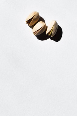 top view of cracked and organic pistachio nuts on white