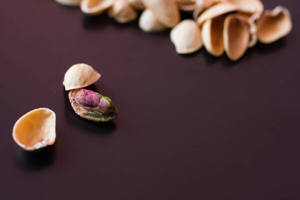 close up view of pistachio near blurred nutshells on black 