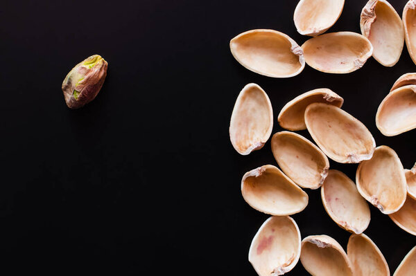 top view of nutshells and tasty pistachio nut isolated on black 