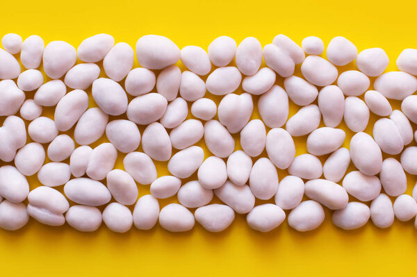 flay lay with row of peeled pine nuts on yellow background