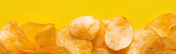 top view of delicious, crunchy and salty potato chips on yellow, banner