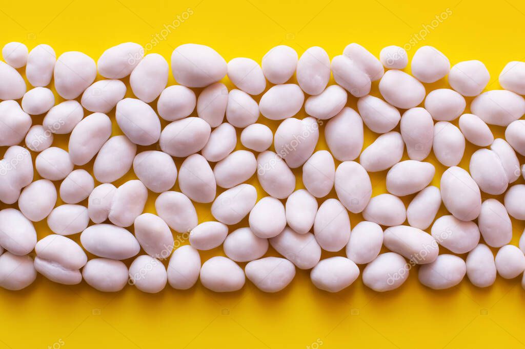 flay lay with row of peeled pine nuts on yellow background