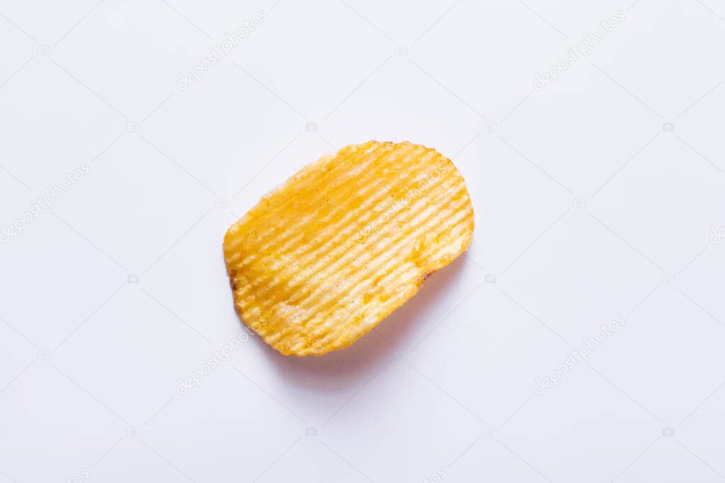 top view of single wavy and salty potato chip on white