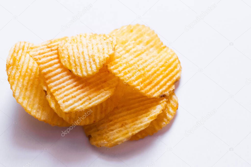 close up view of wavy and salty potato chips on white