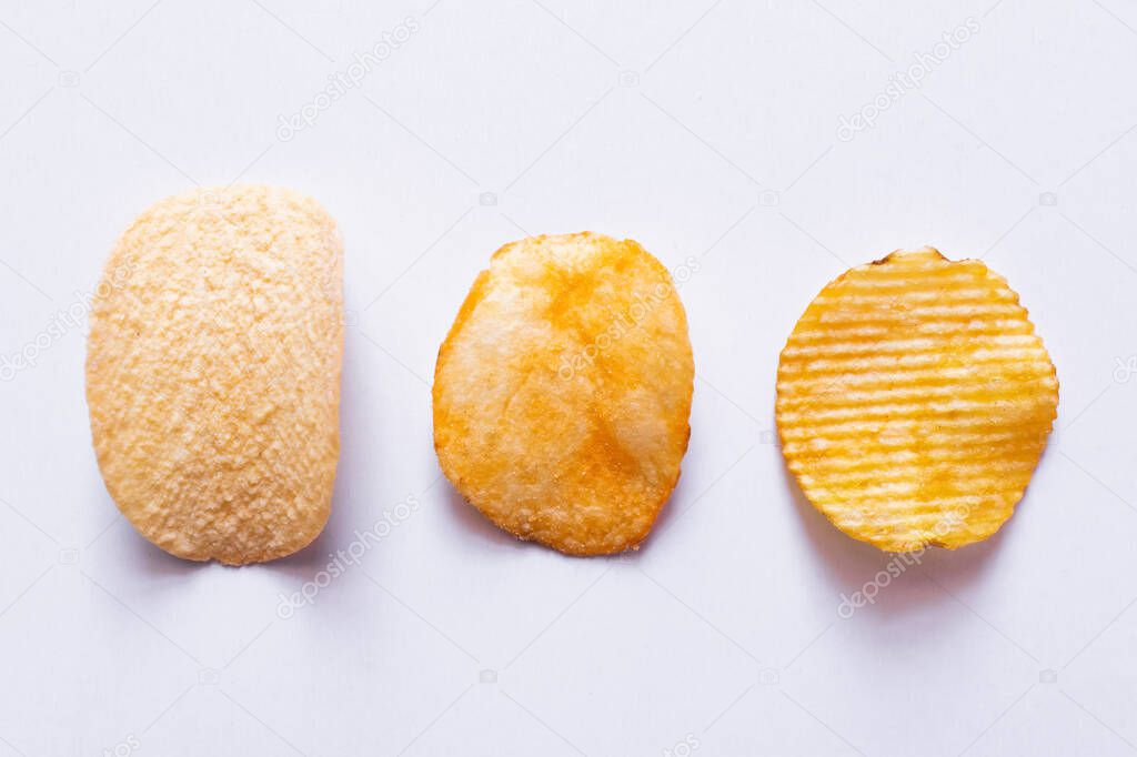 top view of different salty potato chips on white 