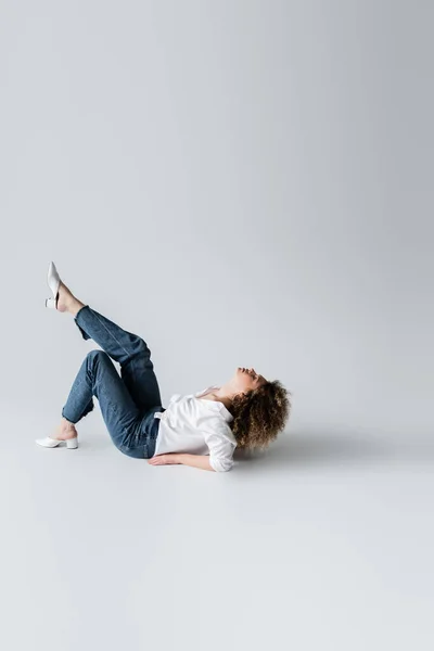 Vista Laterale Della Giovane Donna Riccia Sdraiata Sfondo Bianco — Foto Stock