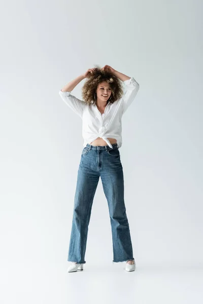 Femme Souriante Chemisier Touchant Les Cheveux Bouclés Sur Fond Blanc — Photo