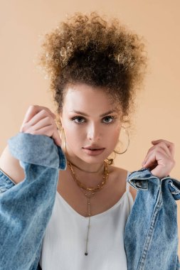Kot ceketli şık bir modelin bej üzerine izole edilmiş kameraya bakışı. 