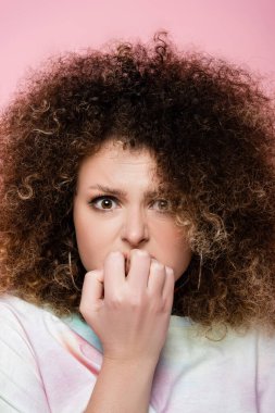 Portrait of nervous curly woman isolated on pink  clipart