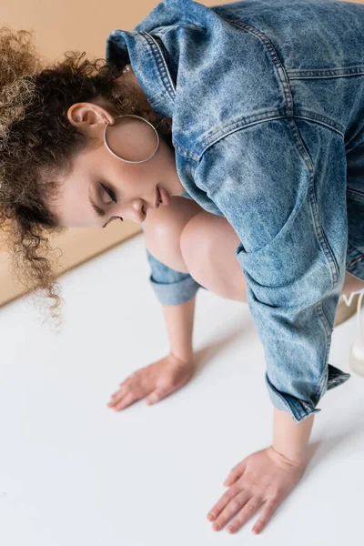 Modelo Encaracolado Elegante Jaqueta Ganga Tocando Chão Fundo Bege — Fotografia de Stock