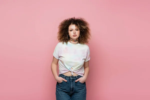 Ung Lockig Kvinna Håller Händerna Fickor Jeans Isolerad Rosa — Stockfoto