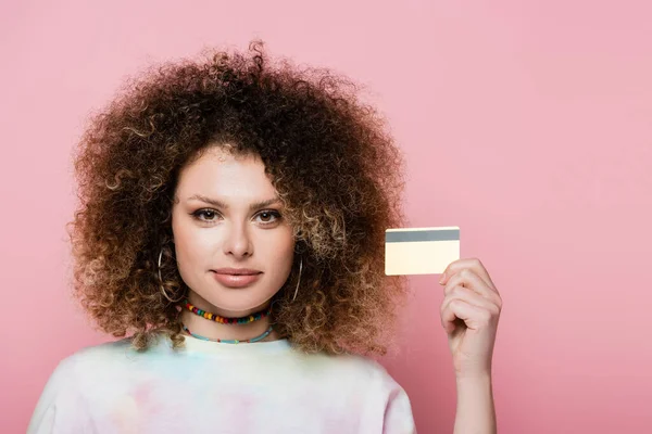 Krullende Vrouw Met Credit Card Kijken Naar Camera Geïsoleerd Roze — Stockfoto