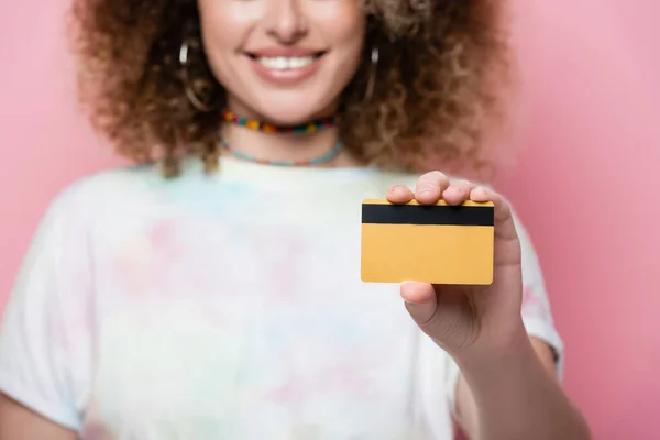 ピンクの上に隔離されたクレジットカードを保持しているぼやけた笑顔の女性のトリミングビュー — ストック写真
