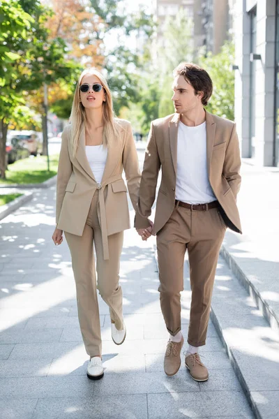 Full Length Brunette Man Blonde Woman Beige Suits Holding Hands — Stock Photo, Image