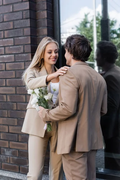 Nöjd Kvinna Vidröra Axeln Ung Man Står Med Blommor Gatan — Stockfoto