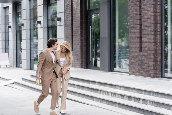 Full Length Smiling Couple Stylish Suits Walking Champagne Bottle Building — Stock Photo, Image