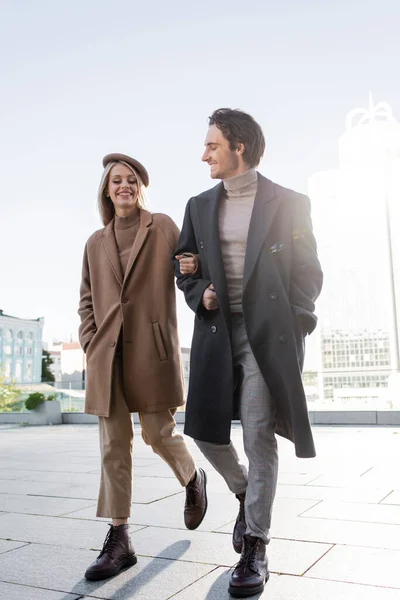 全长的年轻夫妇穿着外套和皮靴在城里散步 — 图库照片