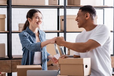 Çevrimiçi web mağazasındaki paketlerin yanında yumruk atan pozitif çok ırklı satıcılar 