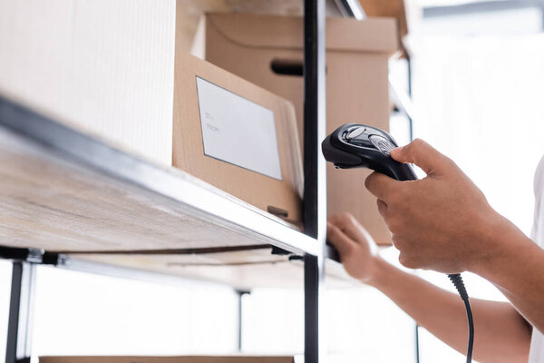 Cropped view of african american seller scanning shipping label on package in store 