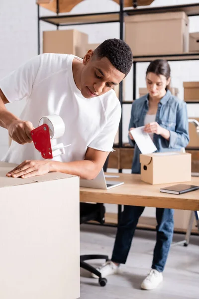 Afrikaanse Amerikaanse Online Webwinkel Eigenaar Verpakking Doos Buurt Wazig Collega — Stockfoto