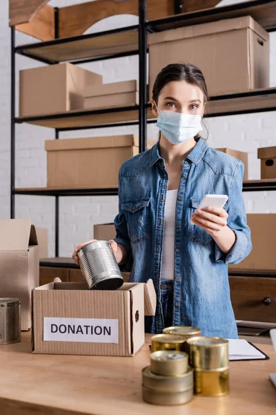 Seller Medical Mask Holding Smartphone Canned Food Donation Box Online — Stock Photo, Image