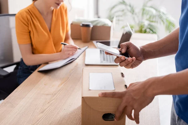 Cropped View African American Courier Holding Smartphone Box Blurred Proprietor — Stock Photo, Image