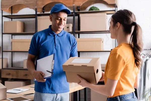 Distribuidor Afroamericano Sujetando Portapapeles Cerca Del Propietario Con Caja Cartón — Foto de Stock