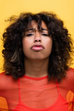 offended african american woman pouting lips and looking at camera isolated on yellow clipart