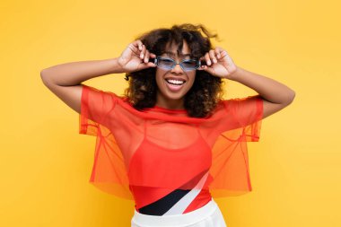 Mutlu Afro-Amerikan kadın moda yaz kıyafetleri içinde güneş gözlüklerini sarıya ayarlıyor.