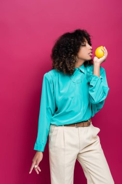 Cyan bluzlu Afro-Amerikan kadın pembe üzerinde aromatik limon tutuyor.