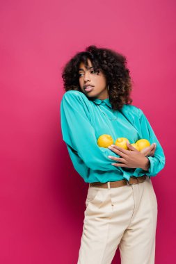 Olgun limonları olan modaya uyan Afro-Amerikalı kadın pembe gözlerden uzakta.