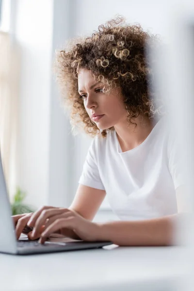 Mulher Concentrada Com Cabelo Ondulado Digitando Laptop Primeiro Plano Desfocado — Fotografia de Stock