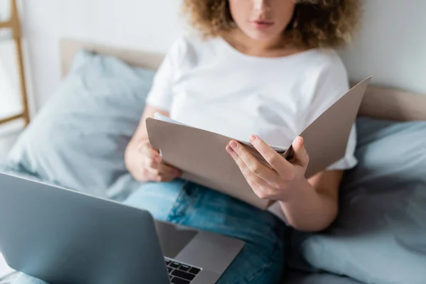 Částečný Pohled Ženu Složkou Notebook Sedí Posteli Rozmazaném Pozadí — Stock fotografie