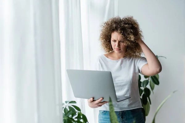 Στοχαστική Γυναίκα Αγγίζει Κυματιστά Μαλλιά Ενώ Κοιτάζοντας Φορητό Υπολογιστή Στο — Φωτογραφία Αρχείου