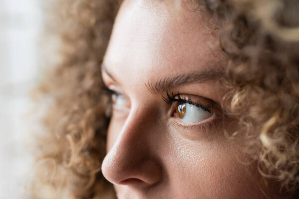 partial view of young woman with curly hair and brown eyes