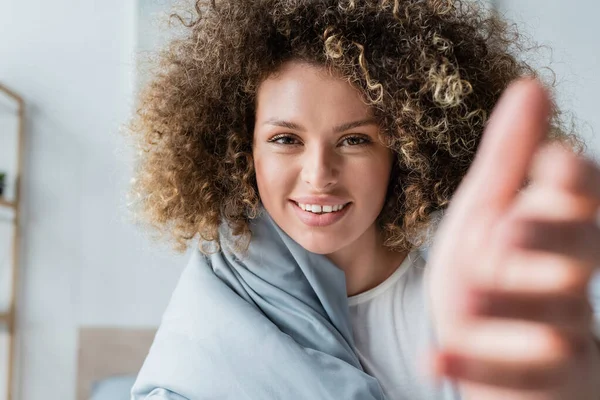 Portrait Cheerful Curly Woman Outstretched Hand Blurred Foreground Bedroom — Stock Photo, Image