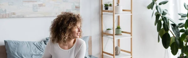 Happy Woman Curly Hair Looking Away Bedroom Rack Potted Plants — Stock Photo, Image