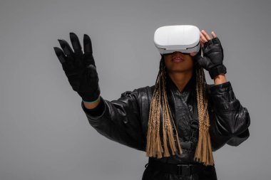 Eldivenli ve vr kulaklıklı Afrikalı Amerikalı kadın gri renkte izole edilmiş. 