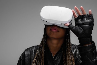 African american woman in leather glove using vr headset isolated on grey  clipart