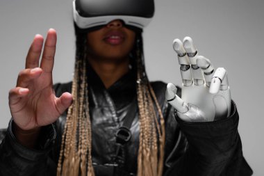 Sanal gerçeklikteki bulanık Afrikalı Amerikalı kadın. Robot eli gri renkte. 