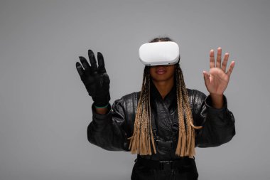 VR kulaklıklı Afrikalı Amerikalı kadın ve siber eldiven oyunu Grey 'de izole edilmiş. 