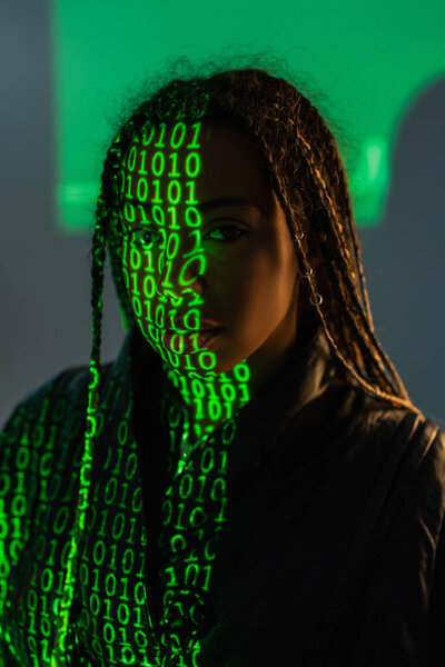 African american woman with projection of computer code looking at camera on grey background 