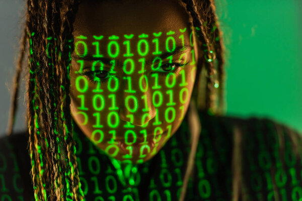 African american woman with projection of binary code on grey background 