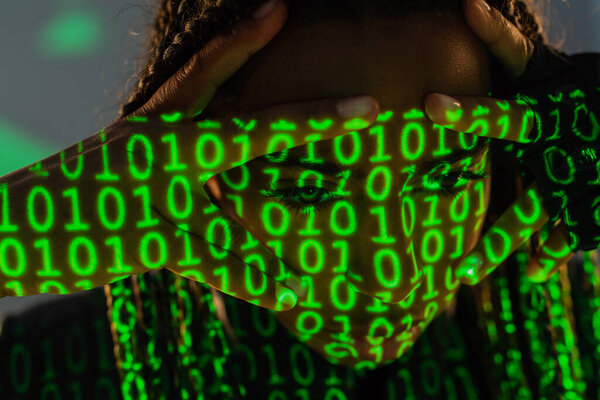 African american woman with projection of green binary code on grey background 