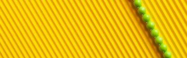 top view of small green balls on striped yellow background with copy space, banner clipart