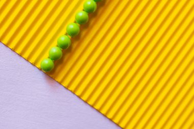 top view of green balls on textured yellow and violet background clipart