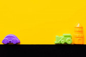 vrchní pohled na věž hraček v blízkosti barevných plastových vozidel na černém a žlutém pozadí