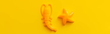 top view of starfish and shrimp toys on bright yellow background, banner clipart