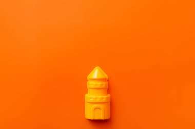 top view of bright yellow plastic tower on orange background clipart